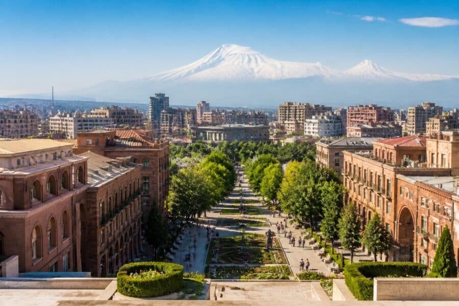 Vista urbana de Ierevan, com edifícios de pedra rosada, árvores e o Monte Ararat ao fundo.